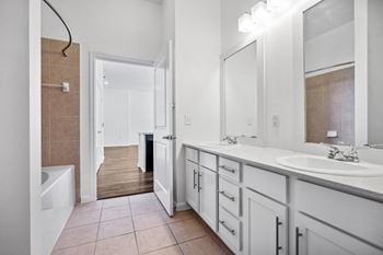 A bathroom with white cabinets and a large mirror and a tub